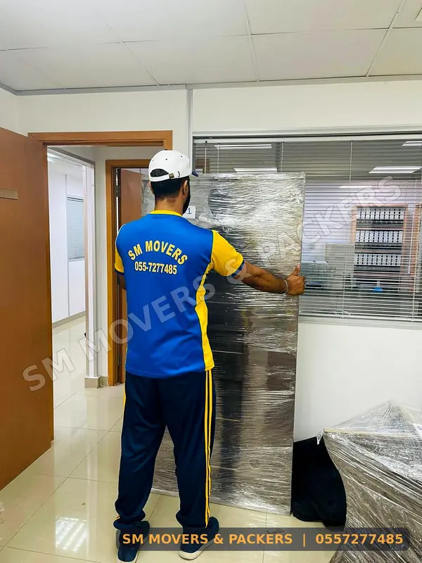 Crew moving a wrapped cabinet in an office